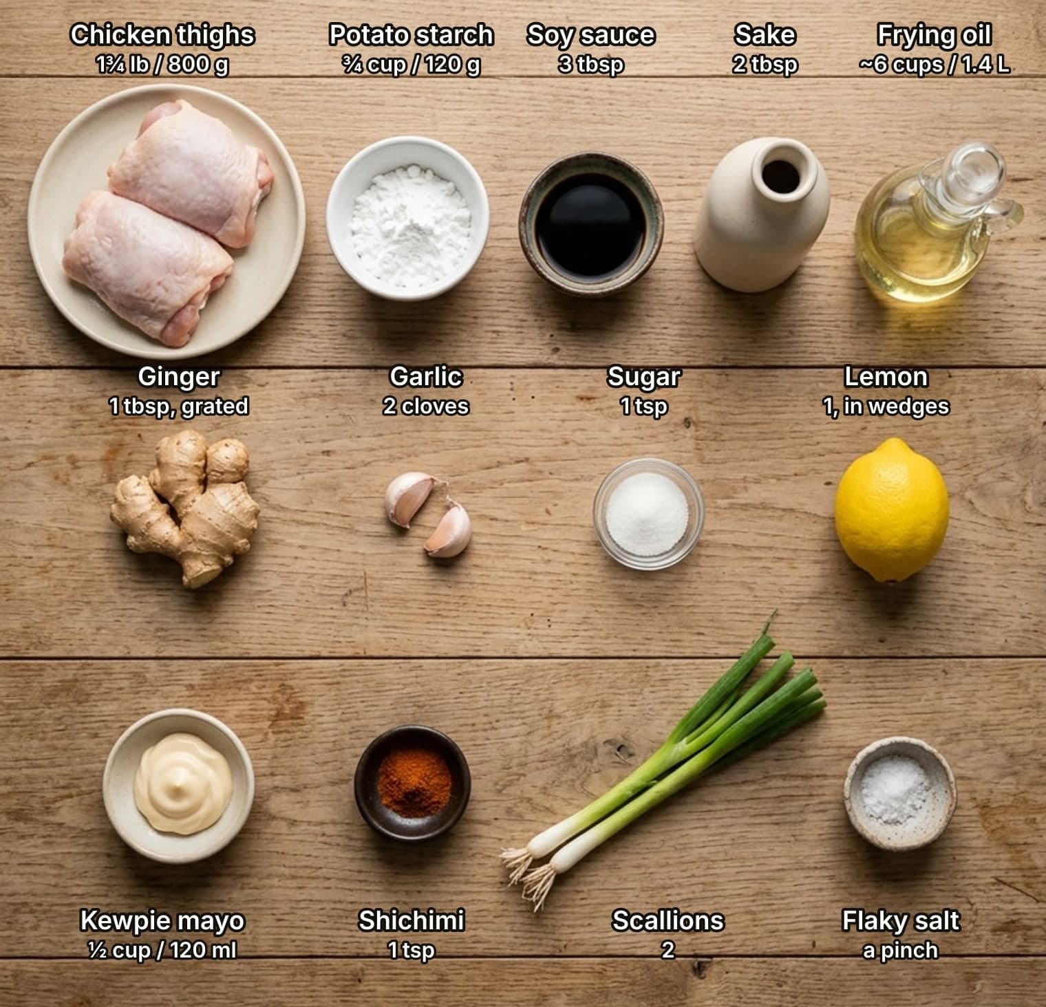 All thirteen karaage ingredients laid out overhead on a wooden kitchen counter and labelled with quantities: chicken thighs, potato starch, soy sauce, sake and frying oil on top; ginger, garlic, sugar and a lemon in the middle; Kewpie mayonnaise, shichimi, scallions and flaky salt below.