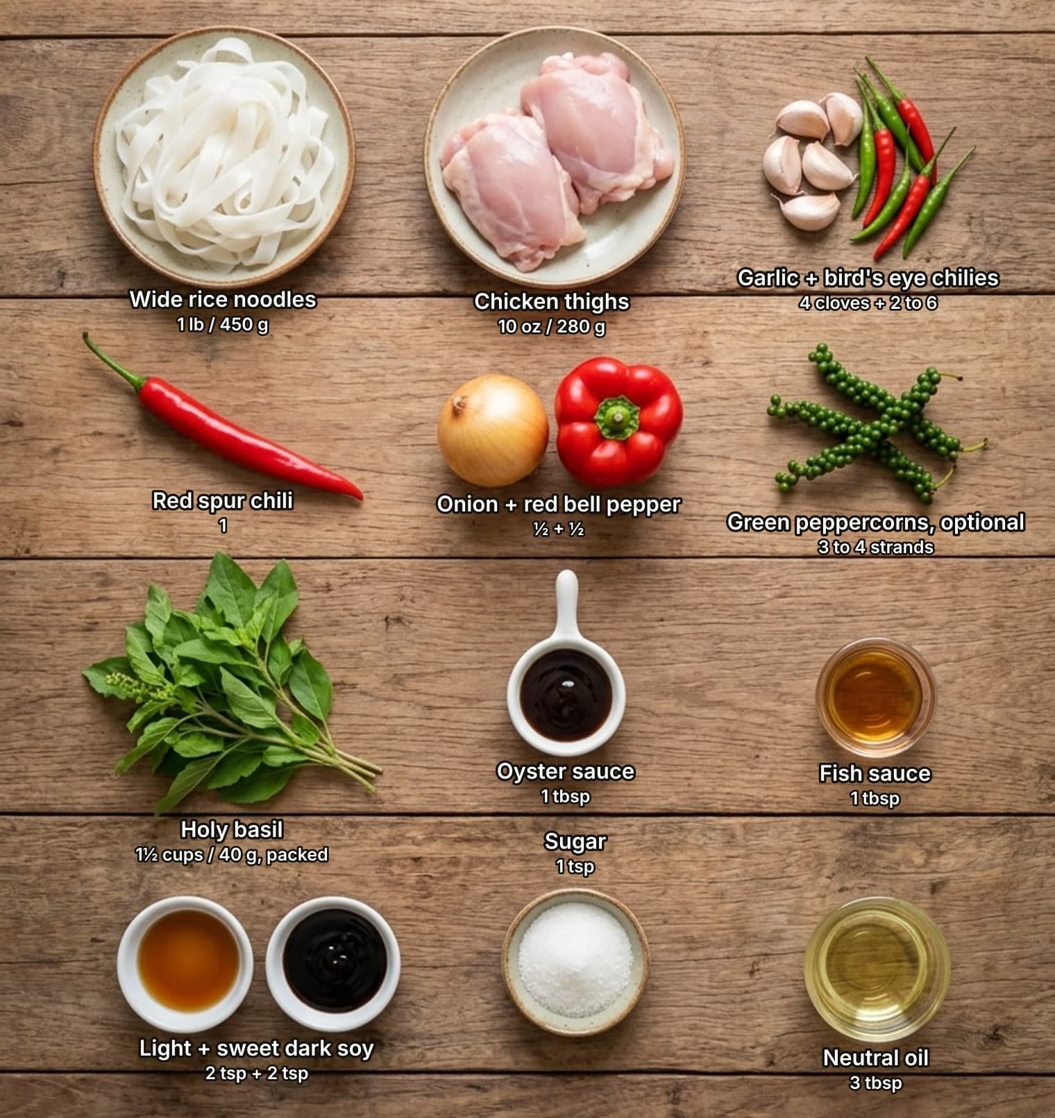 Drunken noodle ingredients laid out overhead on a wooden counter and labelled with quantities: a plate of fresh wide rice noodles, two raw chicken thighs on a plate, and garlic cloves beside red and green bird's eye chilies across the top; a long red chili, a yellow onion beside a red bell pepper, and strands of fresh green peppercorns in the second row; a bunch of holy basil and small dishes of oyster sauce and fish sauce in the third row; bowls of light and sweet dark soy sauce, a bowl of sugar and a glass dish of oil below.