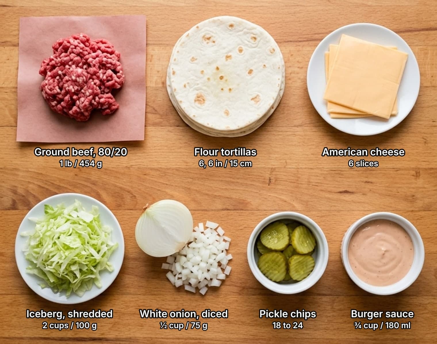Smash burger taco ingredients laid out overhead on a wooden counter and labelled with quantities: a mound of raw ground beef on butcher paper, a stack of small flour tortillas and American cheese slices on a plate across the top; a plate of shredded iceberg lettuce, half a white onion beside a pile of diced onion, a bowl of crinkle-cut dill pickle chips and a bowl of pink burger sauce below.