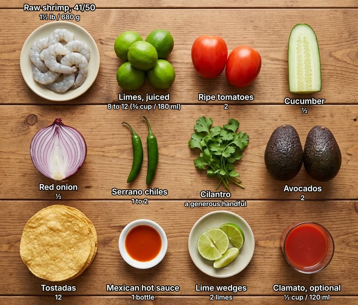 Shrimp ceviche ingredients laid out overhead on a wooden counter and labelled with quantities: raw peeled shrimp on a plate, a pile of limes, two ripe tomatoes and half a cucumber across the top; half a red onion, two serrano chiles, a bunch of cilantro and two avocados in the middle; a stack of tostadas, a small dish of hot sauce, lime wedges on a saucer and a glass of Clamato below.