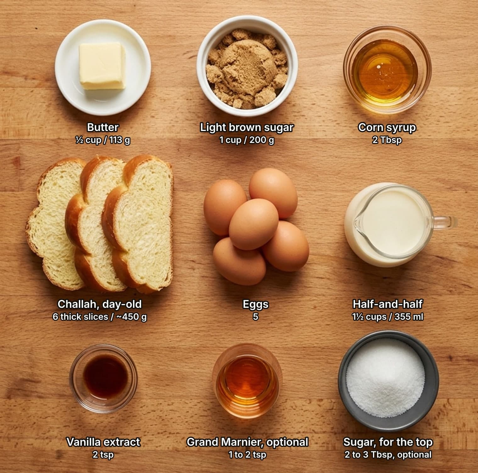 Crème brûlée french toast ingredients laid out overhead on a wooden counter and labelled with quantities: a block of butter on a dish, a bowl of light brown sugar and a glass dish of corn syrup across the top; thick slices of challah, a cluster of brown eggs and a glass jug of half-and-half in the middle; a glass dish of vanilla extract, a small glass of Grand Marnier and a dark bowl of sugar for the top below.